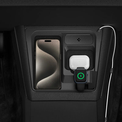 Draufsicht einer iPhone-Ladestation für Tesla mit Smartphone, weißem Ohrhörer-Case und Smartwatch mit grünem Ladesymbol.