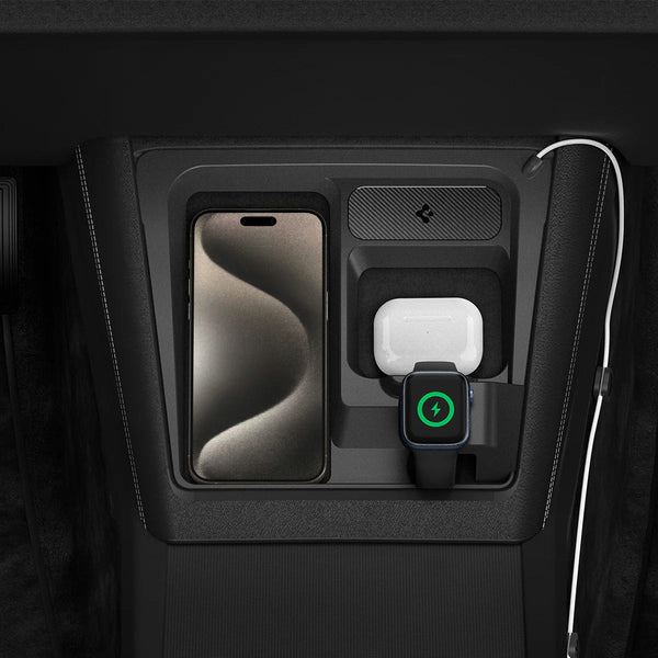Draufsicht einer iPhone-Ladestation für Tesla mit Smartphone, weißem Ohrhörer-Case und Smartwatch mit grünem Ladesymbol.