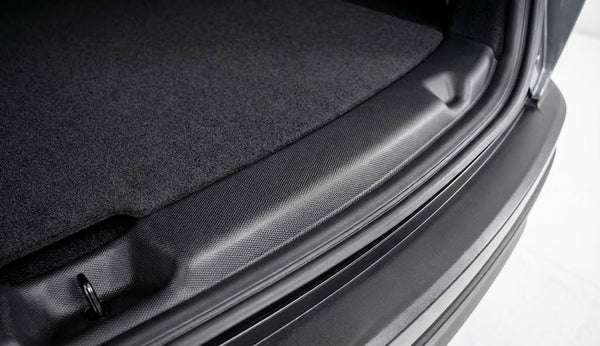 Schwarzer Model Y Ladekantenschutz mit feinem Muster auf der Ladekante, neben dem verkleideten Kofferraumboden und der Gummidichtung.