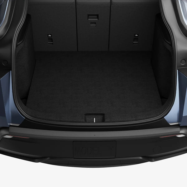 Offener, leerer Kofferraum mit Spigen Ladekantenschutz für Tesla Model Y als dunklem Streifen auf der hinteren Stoßstange.