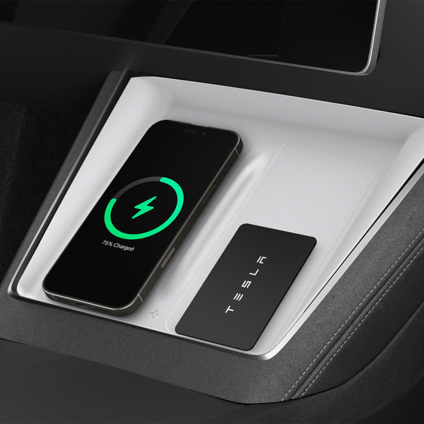 Weiße Spigen-Schutzauflage in der Mittelkonsole, links ein Smartphone mit grünem Ladesymbol und rechts eine schwarze Tesla-Karte.