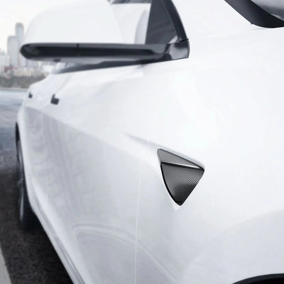 Schwarze Spigen Seitenkamera-Abdeckung im Carbonlook an einem weißen Tesla Model 3 Highland unter dem Außenspiegel
