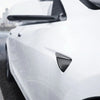Schwarze Spigen Seitenkamera-Abdeckung in Carbonoptik an einem weißen Tesla Model Y Juniper unter dem Außenspiegel