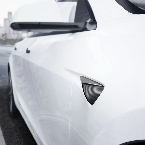 Schwarze Spigen Seitenkamera-Abdeckung in Carbonoptik an einem weißen Tesla Model Y Juniper unter dem Außenspiegel
