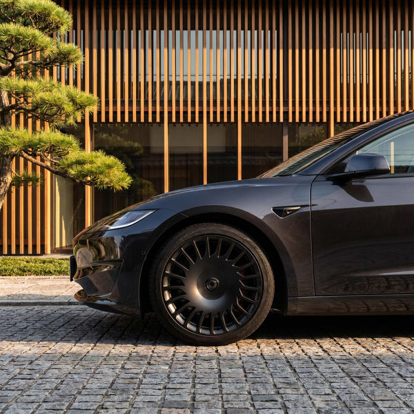 Tesla Model 3 Performance Felgen 19 Zoll The New Aero Razor V2, Detailaufnahme Vorderrad vor moderner Architektur.