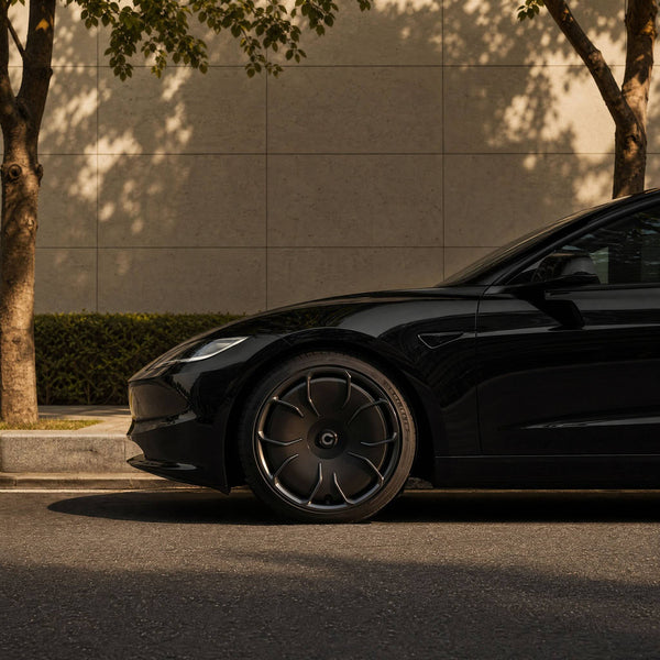 Schwarzes Tesla Model 3 mit CHELA in Glossy Titanium und Satin Carbon, Nahaufnahme der vorderen Felge in warmer Abendsonne.