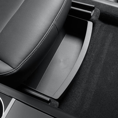 Detailaufnahme der tesla model y organizer tray, die unter dem Vordersitz des Model Y Juniper 2025+ eingeschoben wird und diskreten, leicht zugänglichen Stauraum bietet.