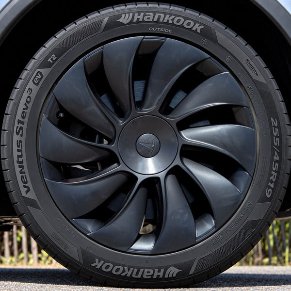 Tesla Model Y Juniper Radkappen 19 Zoll Uberturbine im Detail: schwarze Radkappe mit Tesla-Logo, frontal auf dem Reifen