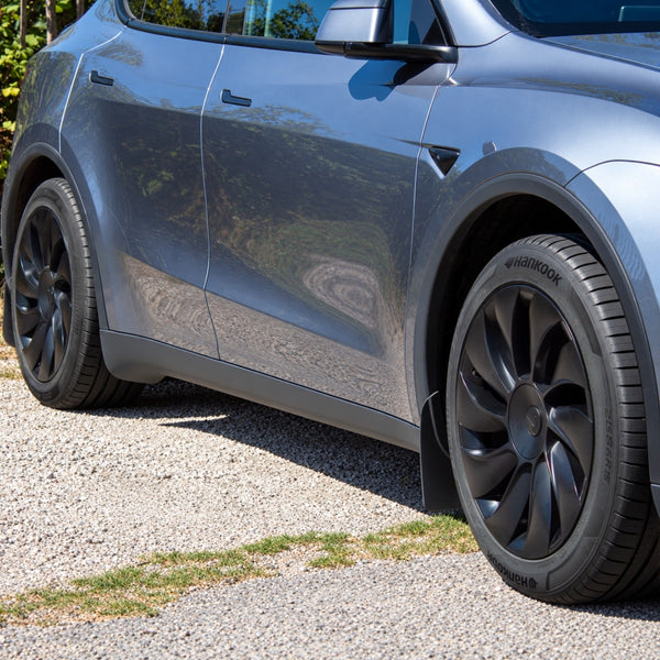 Tesla Model Y Juniper Radkappen 19 Zoll Uberturbine auf beiden sichtbaren Rädern eines grauen Model Y, auf Schotter geparkt