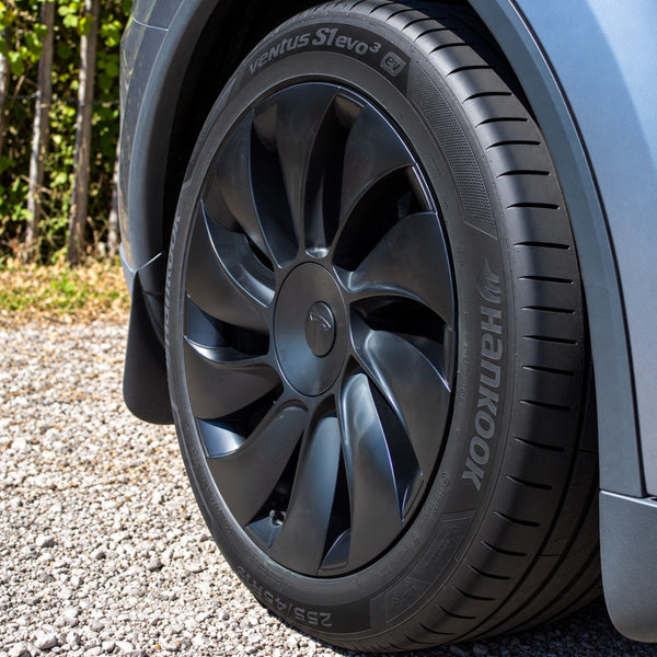 Tesla Model Y Juniper Radkappen 19 Zoll Uberturbine von der Seite: schwarze gebogene Speichen, runde Mittelkappe und Ventil