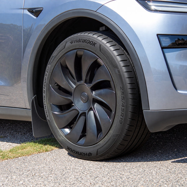 Tesla Model Y Juniper Radkappen 19 Zoll Uberturbine am Vorderrad, mit Tesla-Logo und grauer Frontstoßstange im Bild