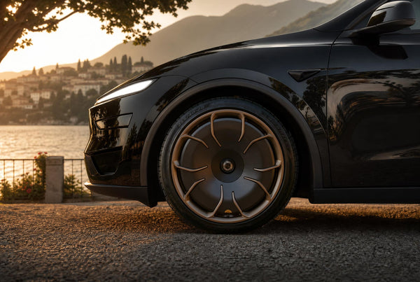 Schwarzes Tesla Model Y Juniper mit CHELA Felgen in Matte Bronze und Satin Carbon, Nahaufnahme am Wasser bei Sonnenuntergang.