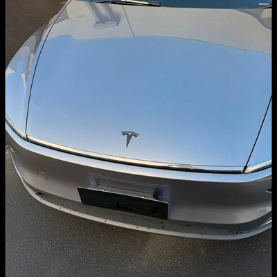 Tesla Logo Model Y Juniper montiert auf grauer Tesla Model Y Front mit modernem Tesla Model Y Emblem Schwarz Design.