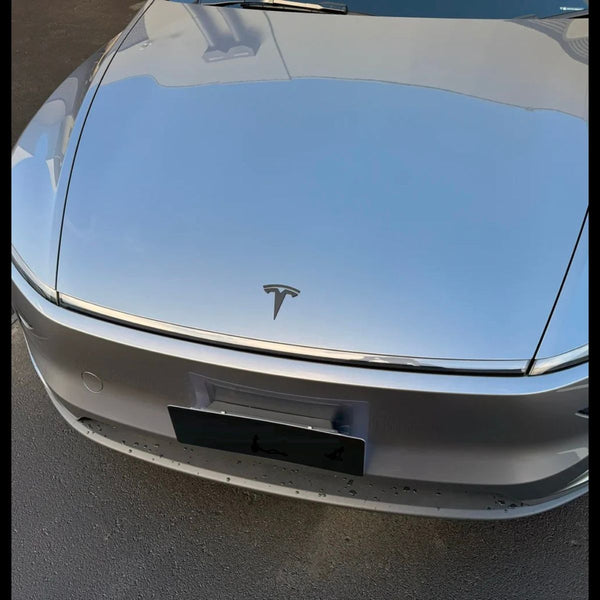 Tesla Logo Model Y Juniper montiert auf grauer Tesla Model Y Front mit modernem Tesla Model Y Emblem Schwarz Design.