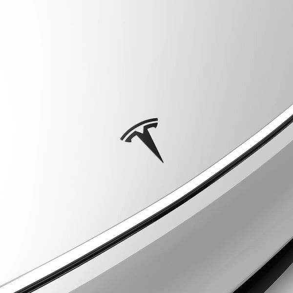 Detailaufnahme vom Tesla Model Y Logo Schwarz auf weißer Motorhaube mit hochwertigem Tesla Model Y Emblem Schwarz Finish.