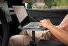 Beifahrer bedient einen Laptop auf einem schwarzen Tesla Model Y Tisch; Halterung und Drehknopf unter der Platte sind sichtbar.