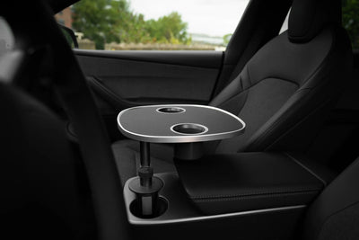 Schwarzer Tesla Model Y Tisch mit zwei runden Öffnungen, in der Mittelkonsole neben dem schwarzen Beifahrersitz montiert.